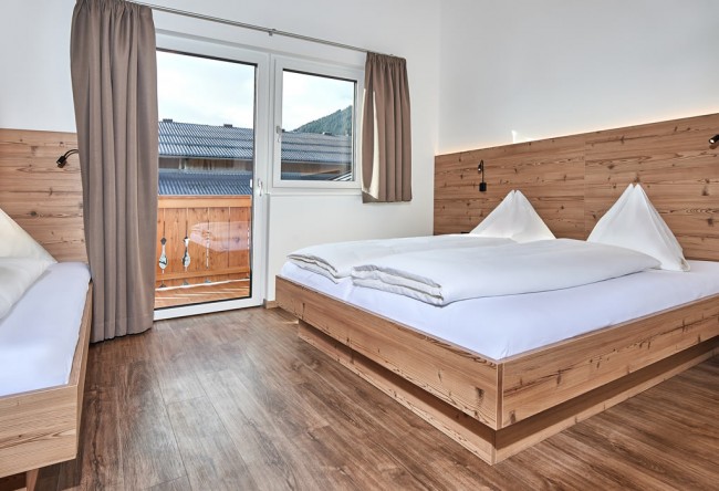 Schlafzimmer mit Doppelbett und Einzelbett mit Zugang zum Balkon
